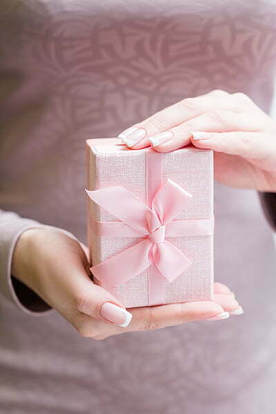 woman holding hands wrapped gift box with bow